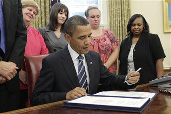 The president signs a $26 billion jobs bill to protect 300,000 nonfederal government workers Wednesday as three out-of-work teachers look on. AP